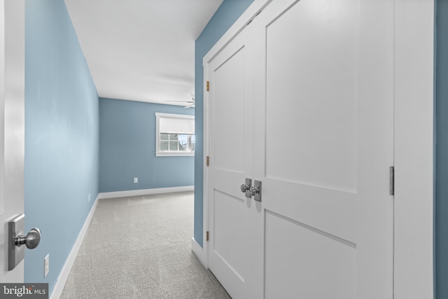 hall featuring baseboards and light carpet