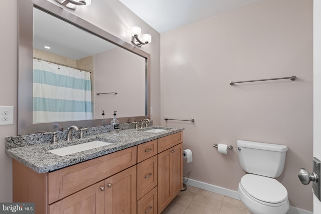 bathroom featuring tile patterned flooring, double vanity, toilet, and a sink