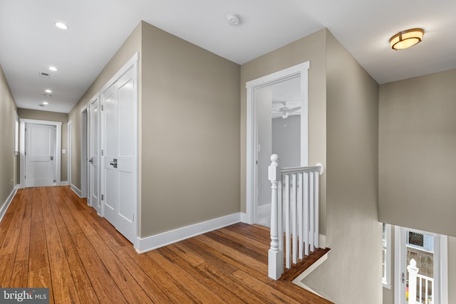 corridor with hardwood / wood-style flooring, recessed lighting, an upstairs landing, and baseboards