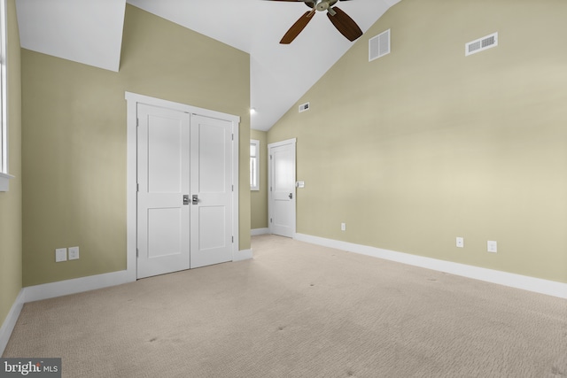 unfurnished bedroom with visible vents, light colored carpet, and high vaulted ceiling