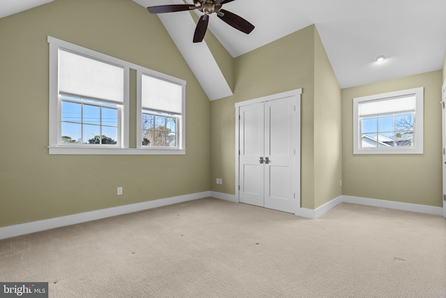 unfurnished bedroom with lofted ceiling, multiple windows, baseboards, and light carpet