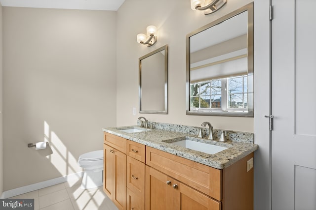 bathroom featuring tile patterned floors, toilet, double vanity, and a sink