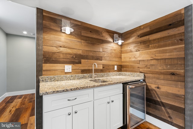 kitchen with a sink, dark wood-style floors, light stone countertops, and beverage cooler