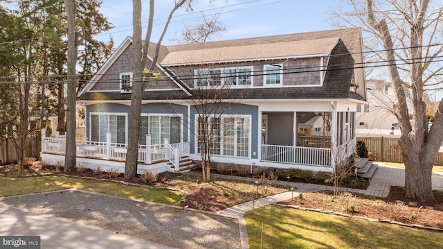 view of front of property featuring a balcony, roof with shingles, covered porch, and fence