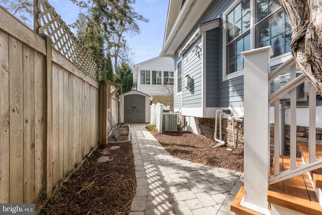 view of home's exterior with a fenced backyard, central AC unit, an outdoor structure, and a shed