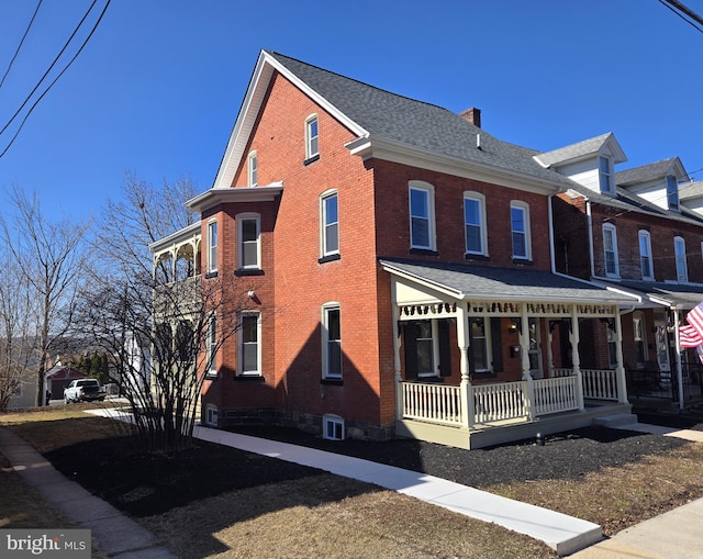 view of side of property with brick siding, a porch, a chimney, and a shingled roof