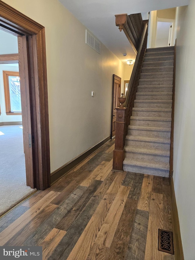 stairway featuring visible vents, baseboards, and wood finished floors