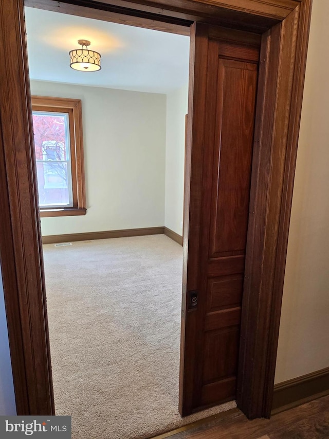 hallway with baseboards and carpet