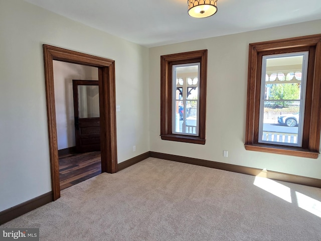 spare room with baseboards and light colored carpet