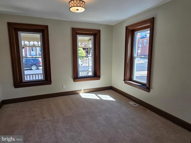 carpeted empty room with visible vents and baseboards