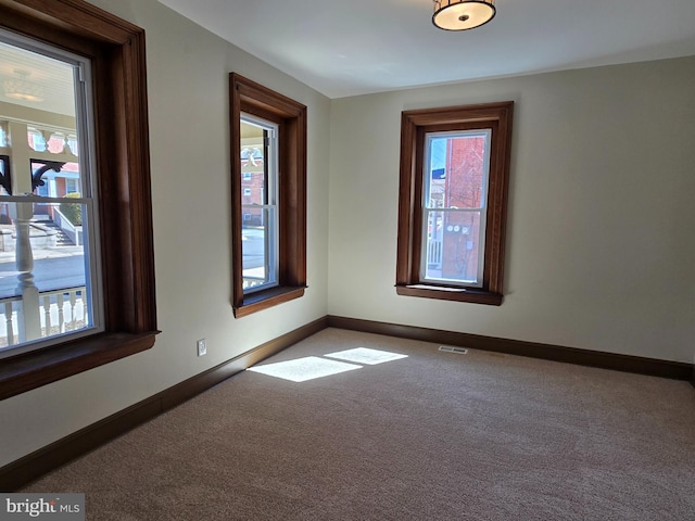 carpeted spare room with visible vents and baseboards