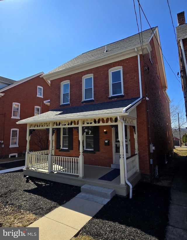 view of front of property featuring brick siding, covered porch, and a shingled roof