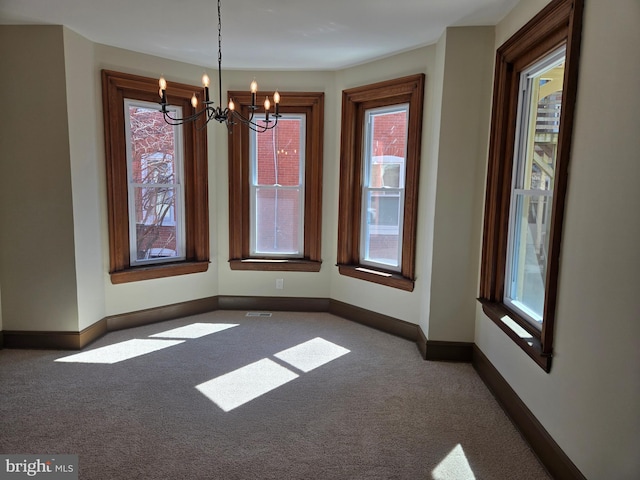 unfurnished dining area with baseboards, carpet floors, and an inviting chandelier