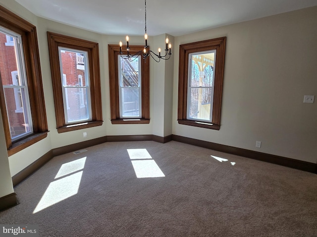 unfurnished dining area featuring a notable chandelier, baseboards, visible vents, and carpet floors