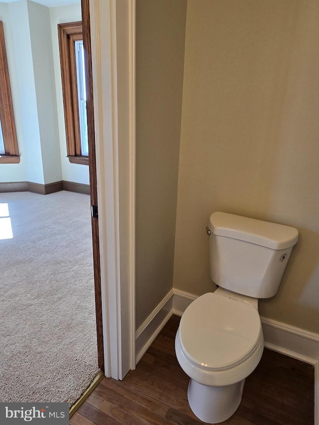 bathroom with toilet, baseboards, and wood finished floors