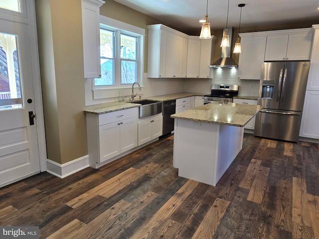 kitchen featuring backsplash, appliances with stainless steel finishes, white cabinets, wall chimney exhaust hood, and a sink