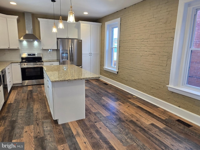 kitchen with dark wood finished floors, wall chimney exhaust hood, appliances with stainless steel finishes, and a center island