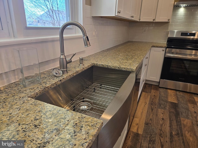 kitchen featuring dark wood-style floors, decorative backsplash, electric stove, and wall chimney range hood