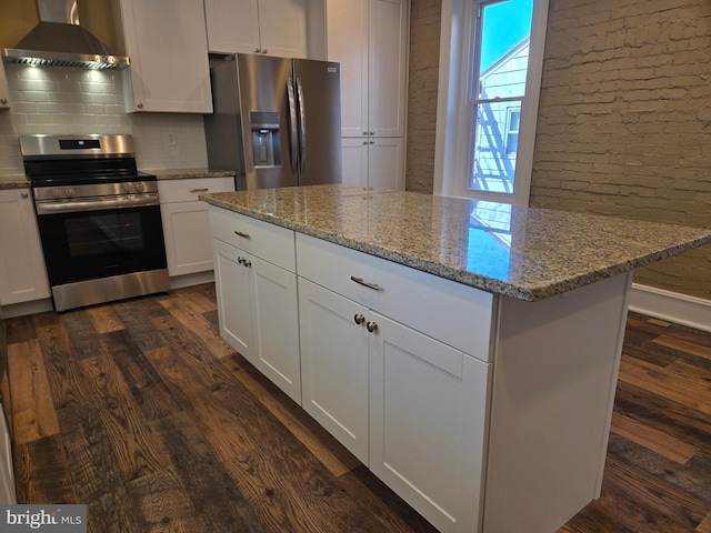 kitchen featuring light stone counters, stainless steel appliances, wall chimney exhaust hood, and dark wood-type flooring