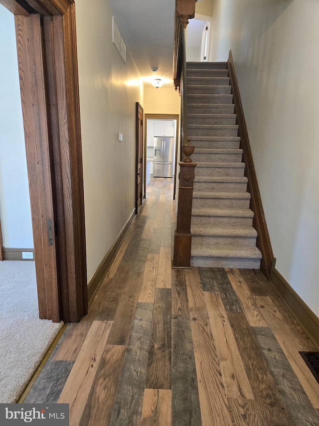 stairway featuring hardwood / wood-style floors, baseboards, and visible vents