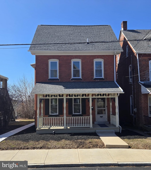 view of front of property featuring a porch, brick siding, and roof with shingles