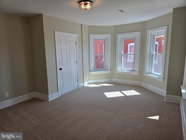 empty room featuring visible vents, baseboards, and carpet