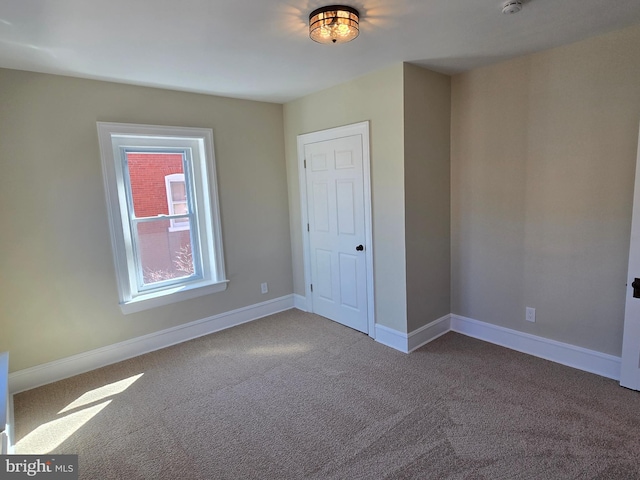 unfurnished room with carpet flooring and baseboards