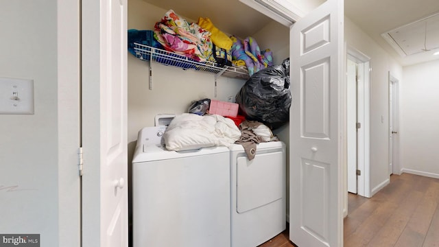 washroom featuring wood finished floors, baseboards, attic access, laundry area, and washing machine and clothes dryer