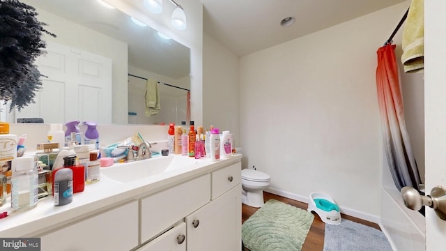 full bathroom featuring vanity, wood finished floors, baseboards, toilet, and a shower with door