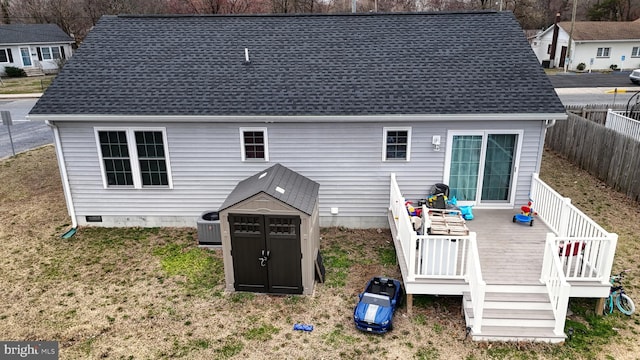 back of house featuring a shingled roof, fence, a wooden deck, a storage shed, and an outdoor structure