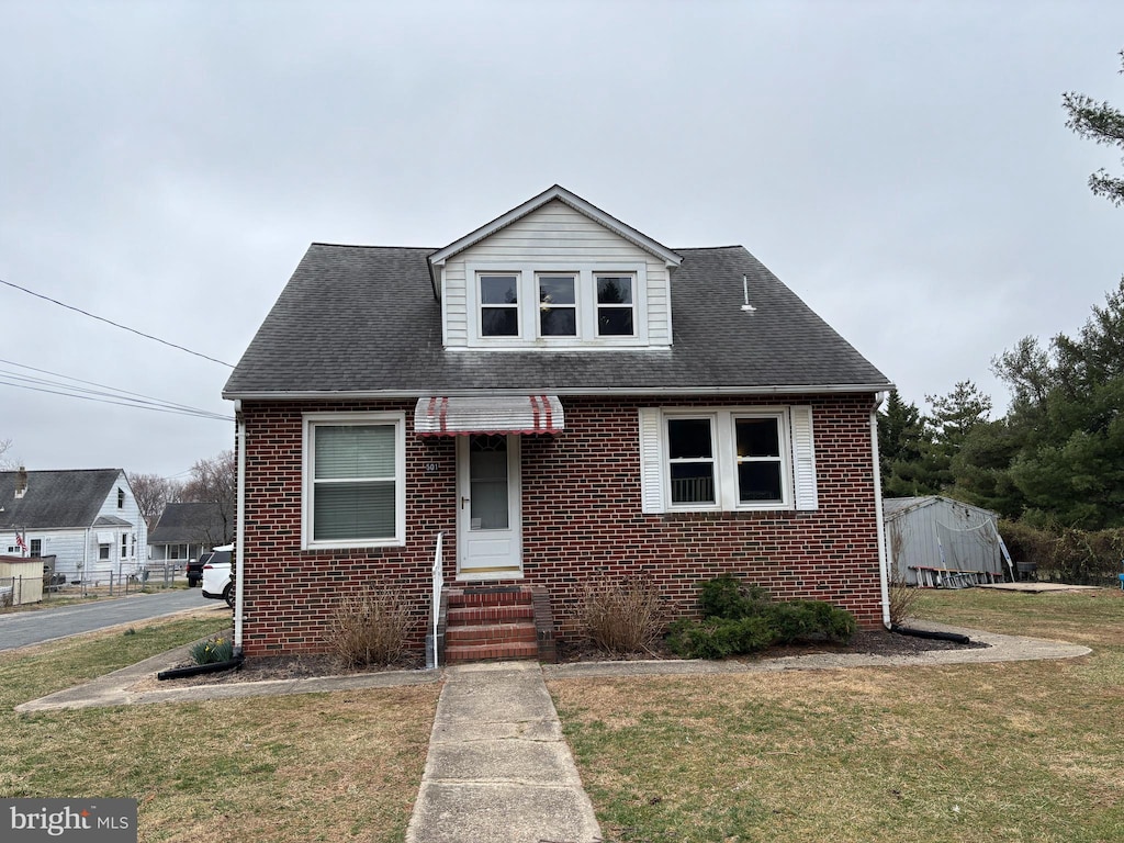 bungalow-style home with a front lawn, brick siding, and roof with shingles