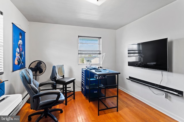 office space with baseboards, wood-type flooring, and a baseboard radiator