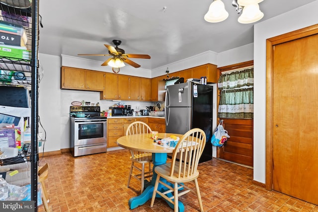 kitchen featuring brown cabinets, ceiling fan with notable chandelier, appliances with stainless steel finishes, light countertops, and baseboards