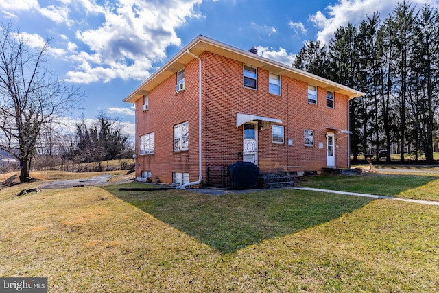 exterior space with brick siding, entry steps, and a yard