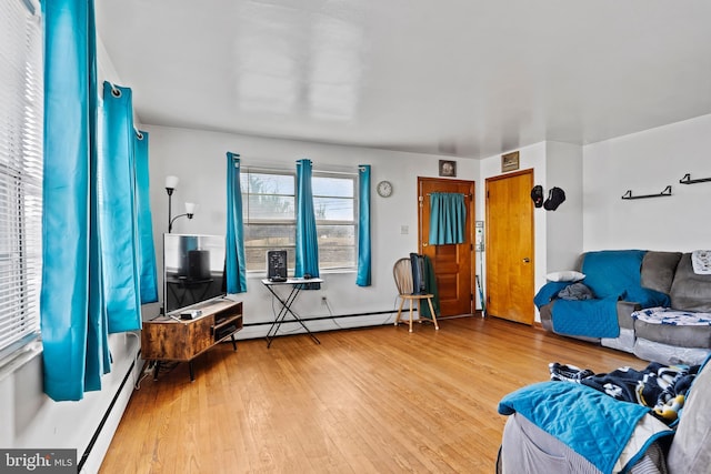 living area featuring a baseboard heating unit and wood finished floors