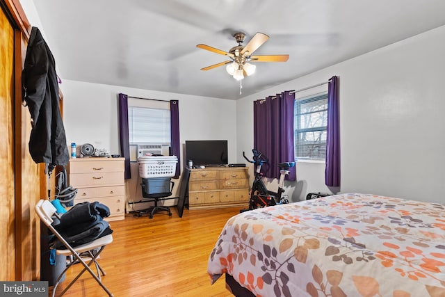 bedroom featuring ceiling fan, a baseboard heating unit, and light wood-style floors