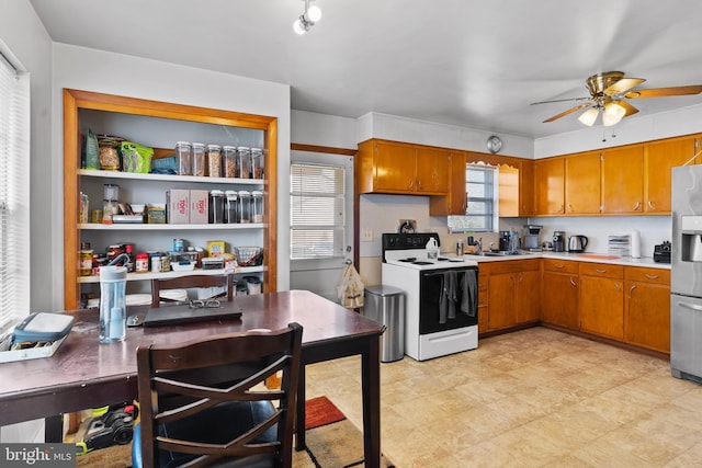 kitchen featuring brown cabinets, white range with electric cooktop, stainless steel fridge, light countertops, and ceiling fan