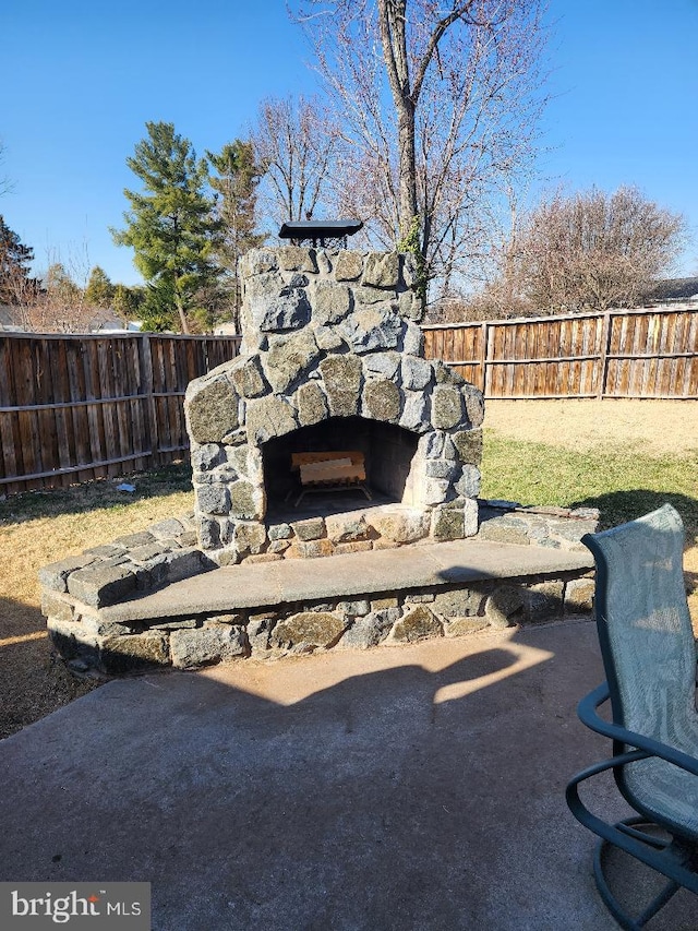 view of patio featuring an outdoor stone fireplace and a fenced backyard