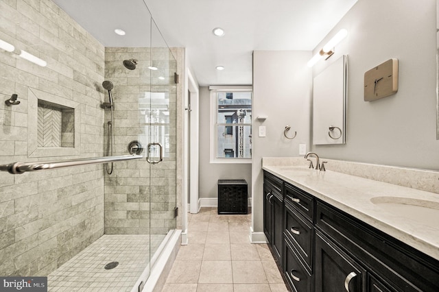 bathroom featuring a shower stall, double vanity, tile patterned floors, and a sink