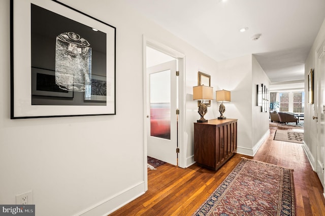 hallway featuring baseboards and wood-type flooring