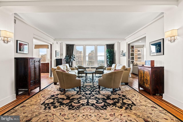 living room featuring visible vents, crown molding, wood finished floors, and baseboards