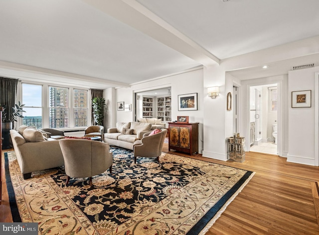 living area featuring beamed ceiling, baseboards, and wood finished floors