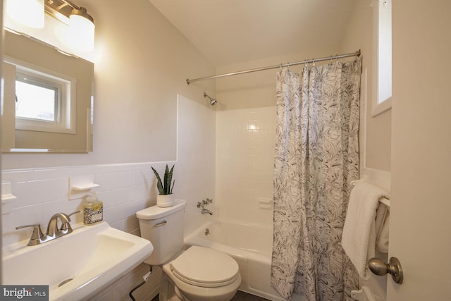 full bathroom featuring a sink, shower / tub combo, wainscoting, tile walls, and toilet