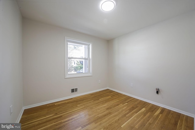 unfurnished room with visible vents, baseboards, and wood finished floors