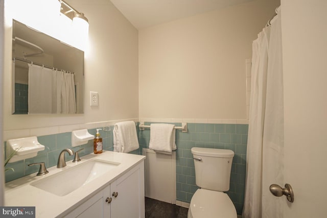 bathroom featuring vanity, tile walls, toilet, and a wainscoted wall