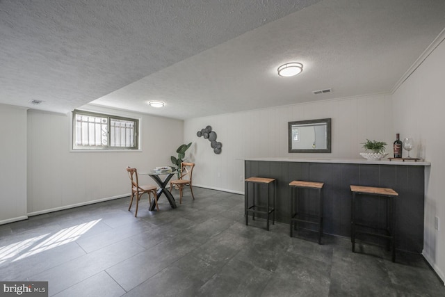 dining space with visible vents, baseboards, a textured ceiling, and a dry bar