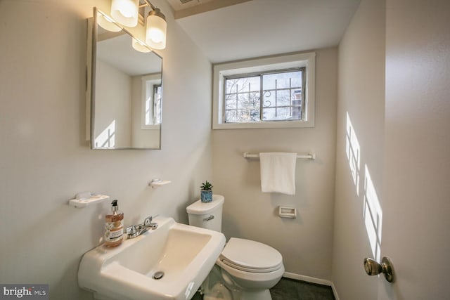 bathroom featuring toilet, baseboards, and a sink