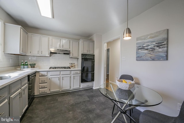 kitchen featuring under cabinet range hood, pendant lighting, light countertops, decorative backsplash, and stainless steel appliances