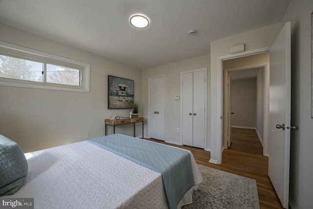 bedroom with baseboards, multiple closets, and wood finished floors