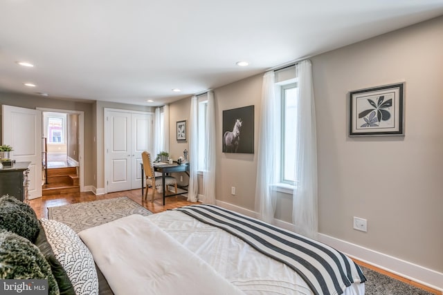 bedroom with recessed lighting, wood finished floors, baseboards, and a closet